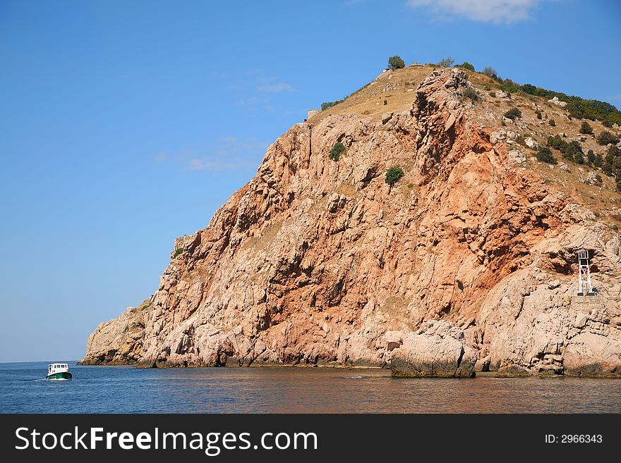 The small ship sail near the cliff in Crimea