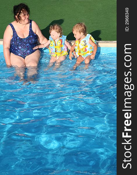 The grandmother and children sit at pool.