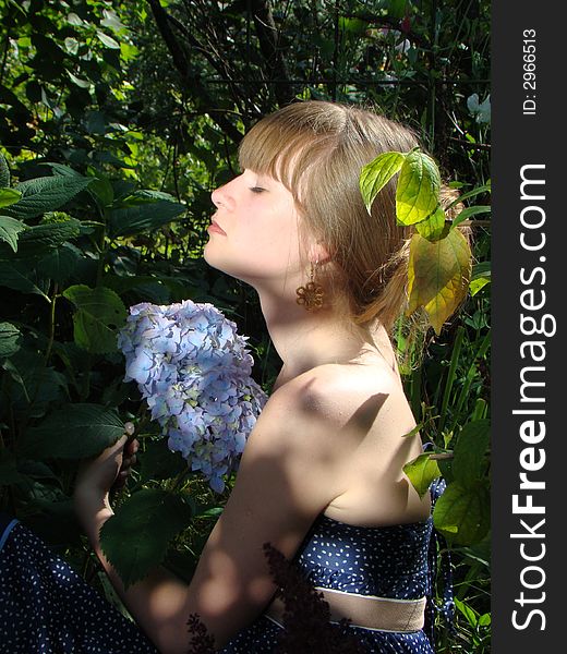 The young girl is in a garden. In a garden the fine blue flower blossoms. It enjoys this flower. The young girl is in a garden. In a garden the fine blue flower blossoms. It enjoys this flower.