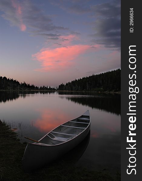 Evening sunset in soft pink and blue light and canoe in lake. Evening sunset in soft pink and blue light and canoe in lake