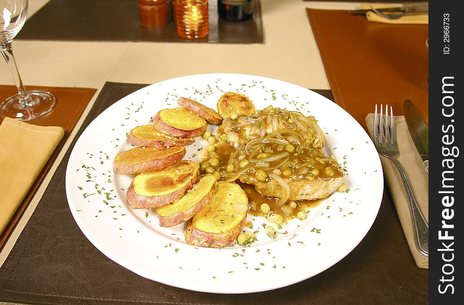 Pork tenderloin served with baked potatoes and an onion and corn sauce