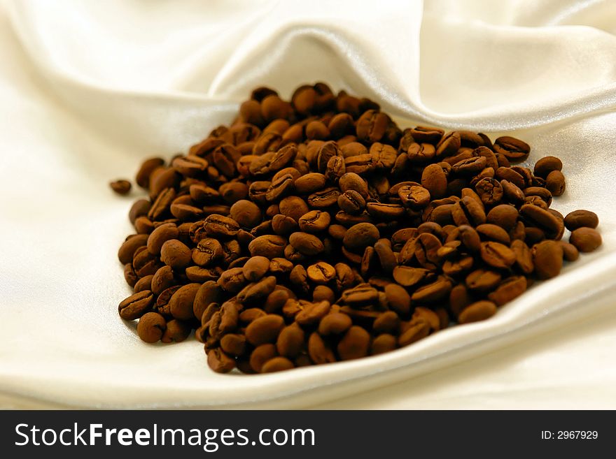 Fresh roasted coffee beans on satin fabric. Fresh roasted coffee beans on satin fabric