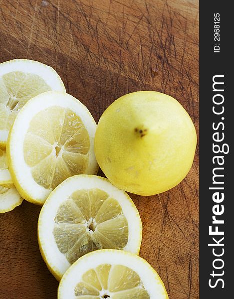 Freshly cut slices of lemon next to an uncut fruit. Freshly cut slices of lemon next to an uncut fruit
