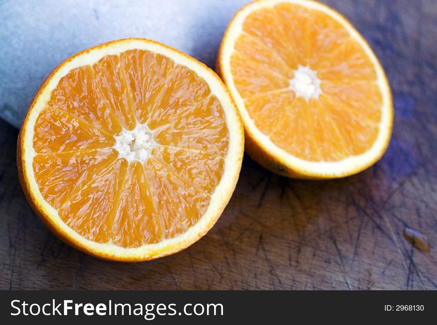 A fresh orange cut in half on a wooden board. A fresh orange cut in half on a wooden board