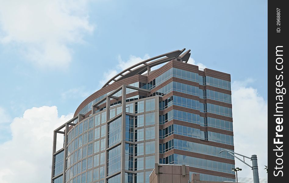 A modern curved brick and glass office building against the sky. A modern curved brick and glass office building against the sky