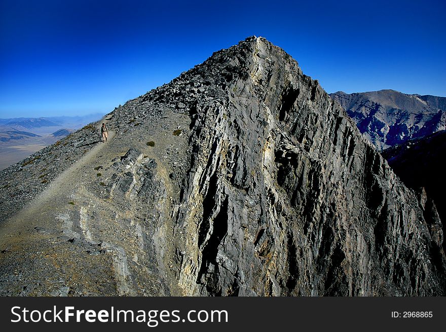 One person walking along trail with mountains in background. One person walking along trail with mountains in background