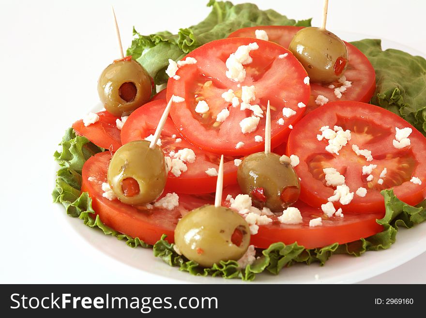 Tomato, feta cheese, olives and lettuce salad over the white background. Tomato, feta cheese, olives and lettuce salad over the white background