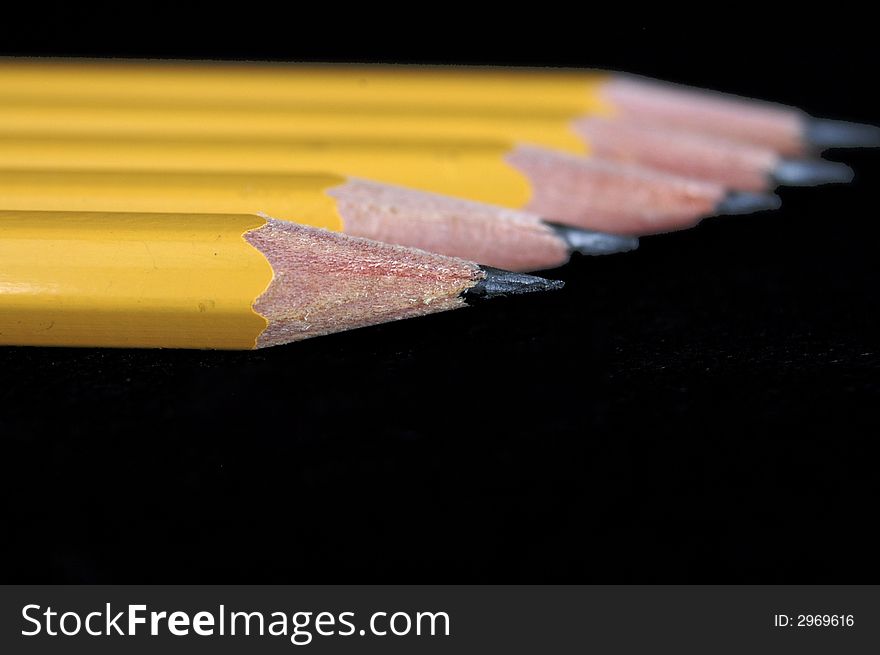 A diagonal row of pencils. Shallow depth of field. Focus is on first pencil. A diagonal row of pencils. Shallow depth of field. Focus is on first pencil.