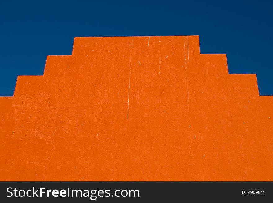 Symmetrical orange stepped structure against blue sky. Symmetrical orange stepped structure against blue sky