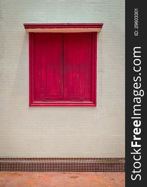 A closed red window on the wall. A closed red window on the wall