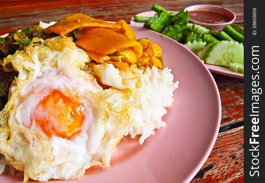 Fried egg topped on the rice with Thai food