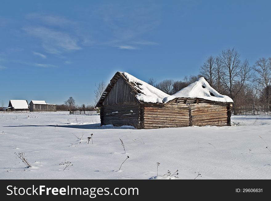 Old wooden barn with a snow-covered sagging roof, winter sunny day. Old wooden barn with a snow-covered sagging roof, winter sunny day