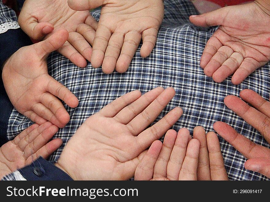 Small Childrens Palms, On A Checkered Cloth Background.