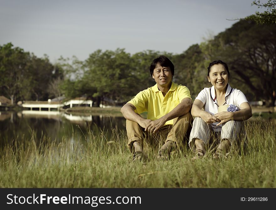 Portrait of beautiful couple sitting on ground in park