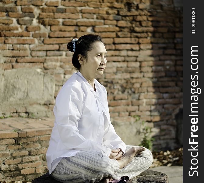 Asian woman meditating yoga in ancient buddhist temple