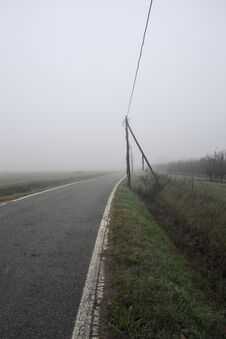 Road Bordered By A Trench And A Power Line Next To Fields On A Foggy Day In The Italian Countryside Royalty Free Stock Photos