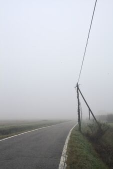 Road Bordered By A Trench And A Power Line Next To Fields On A Foggy Day In The Italian Countryside Stock Photos