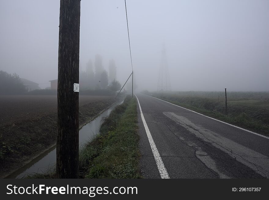 Group of houses by the edge of a country road on a foggy day in autumn