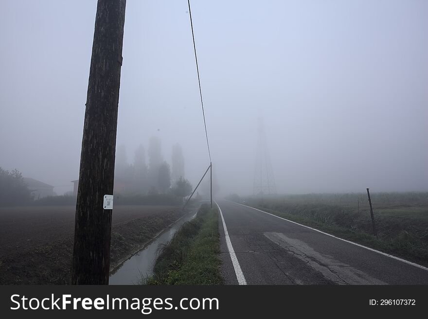 Group of houses by the edge of a country road on a foggy day in autumn