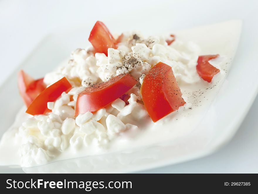The dish from the coottage cheese, the sour cream, tomates, strewn with the Black pepper and salt. The dish from the coottage cheese, the sour cream, tomates, strewn with the Black pepper and salt