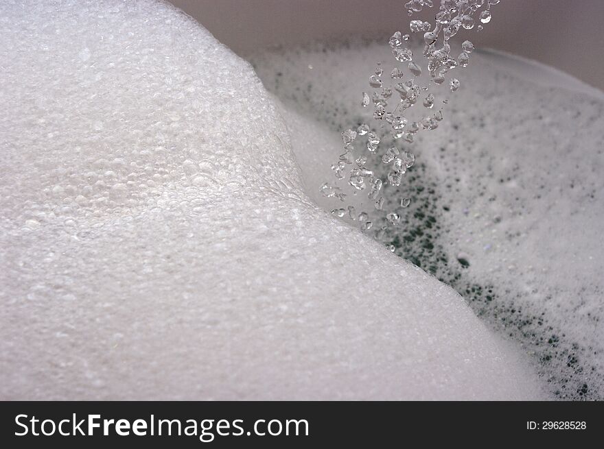 Flow of water droplets into bubbly / foamy bath water. Flow of water droplets into bubbly / foamy bath water