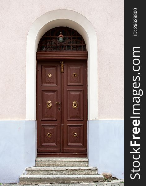 Old wooden church door with gold trim, with an arch, grille and lights, on the cracked concrete steps. Old wooden church door with gold trim, with an arch, grille and lights, on the cracked concrete steps