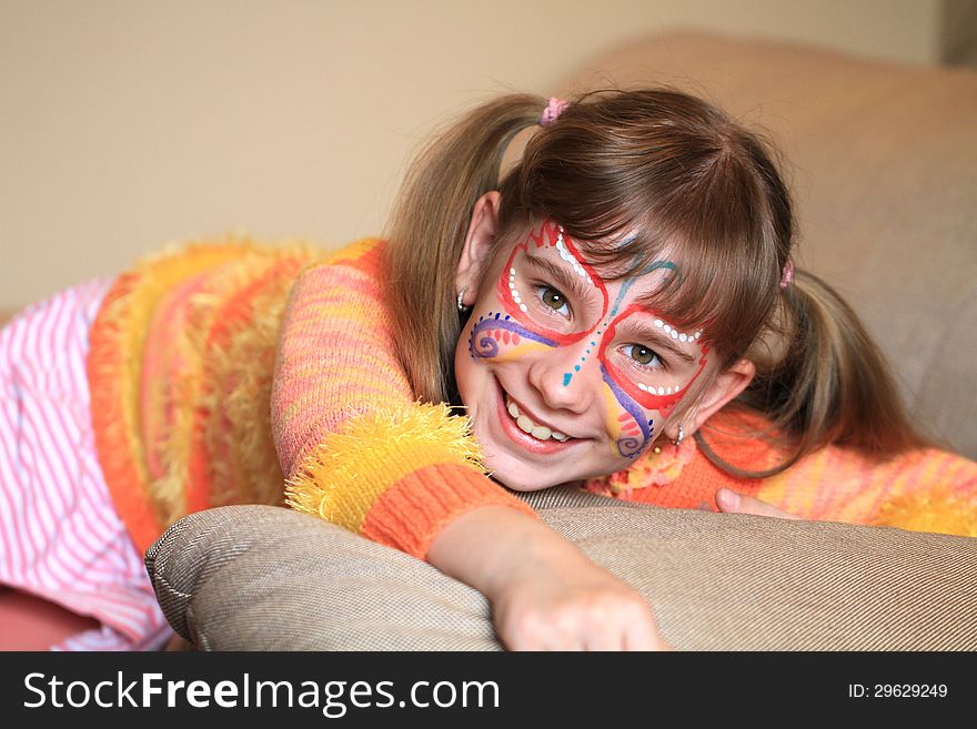 Happy girl with a pattern on the face is sitting o