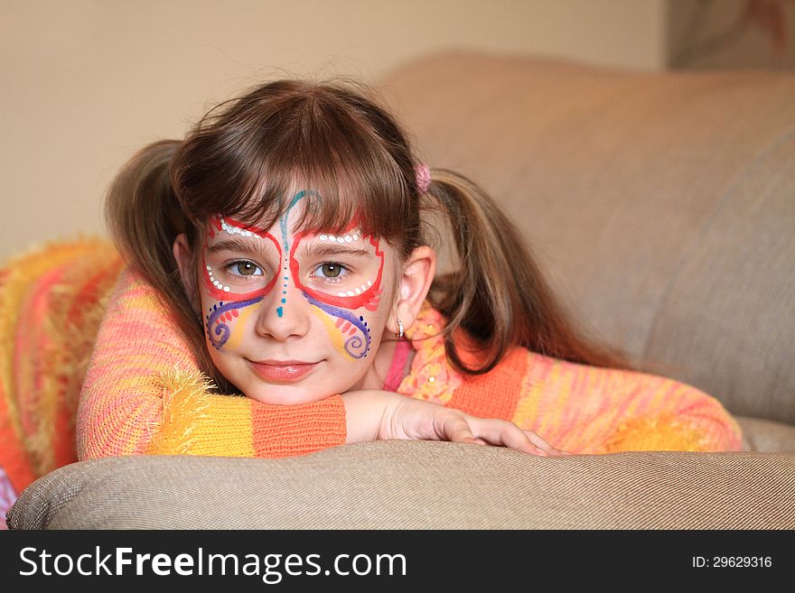 Girl 8 years with a pattern on the face is lying on the sofa and dreaming. Girl 8 years with a pattern on the face is lying on the sofa and dreaming.