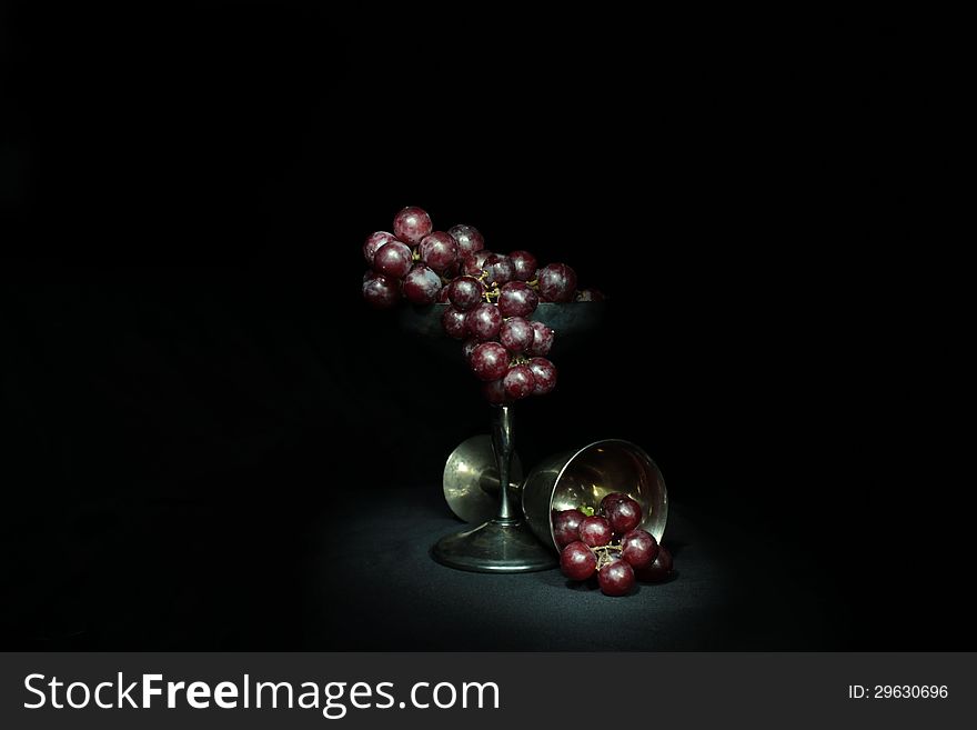 Red grapes in a tarnished silver goblet. Red grapes in a tarnished silver goblet.