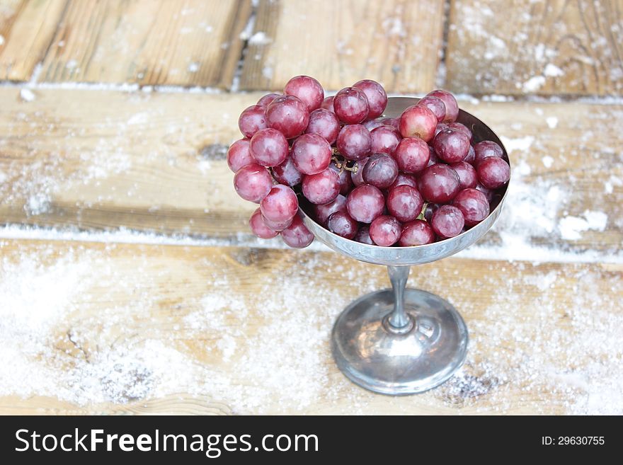 Red grapes in a tarnished silver goblet.