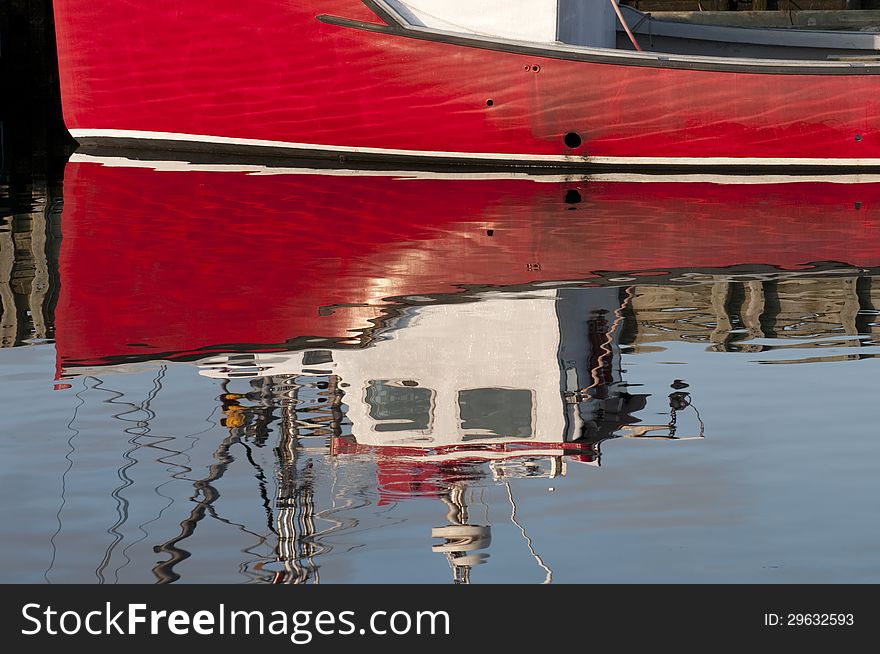 Reflection of a red fishing boat docked at Louisbourg harbor, Nova Scotia. Reflection of a red fishing boat docked at Louisbourg harbor, Nova Scotia