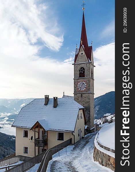 A wintertime view of a small church with a tall steeple in the Sud Tyrol, Italy.