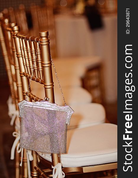 An elegant gold chair and silver purse at formal event.