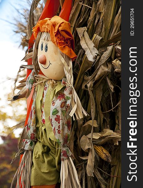 Fall decorations with scarecrow and hay stack.