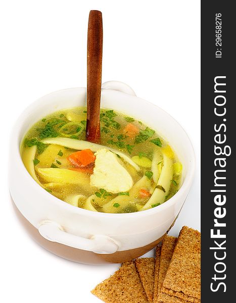 Chicken Noodle Soup with Parsley and Carrot in White Bowl with Wooden Spoon and Crispy Bread closeup on white background