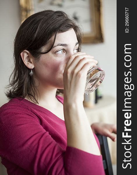 Beautiful young woman in a pink sweater drinks a glass of water. Beautiful young woman in a pink sweater drinks a glass of water.