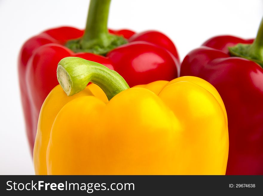 The picture shows 3 peppers in yellow and red. Tabletop with white background.