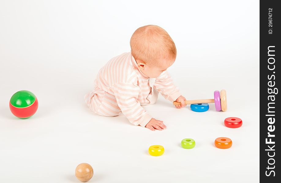 Happy baby playing with a toy pyramid on white background
