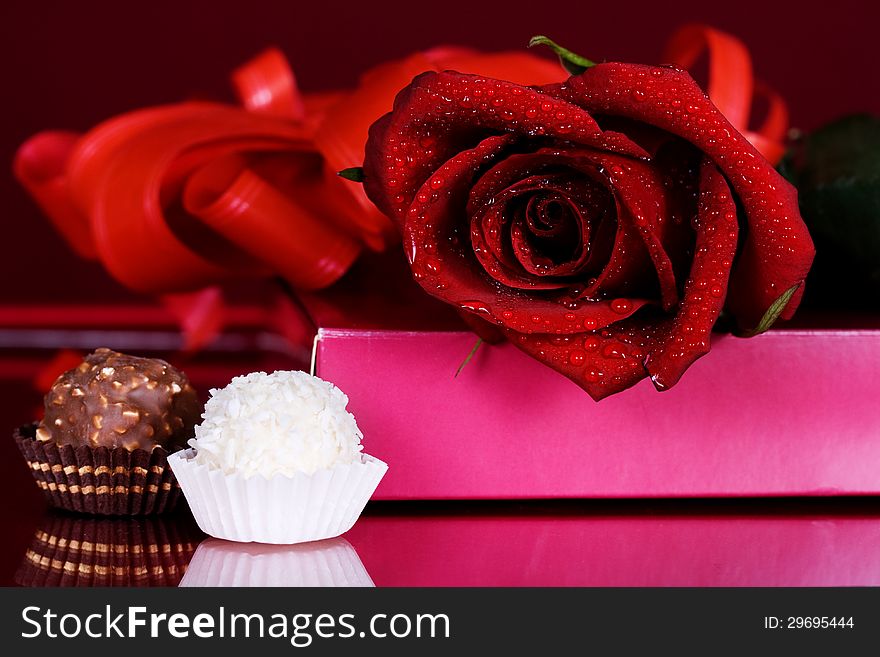 Beautiful red roses with chocolates on a red background. Beautiful red roses with chocolates on a red background
