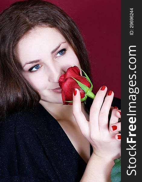 Beautiful woman enjoys the scent of red roses. Beautiful woman enjoys the scent of red roses