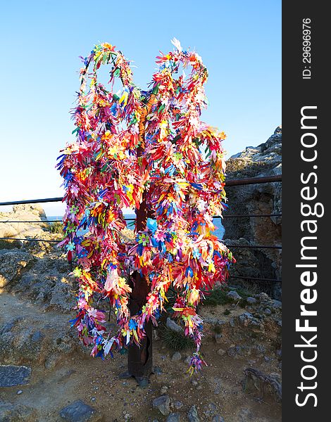 Wish tree decorated colored tape in mountains near sea