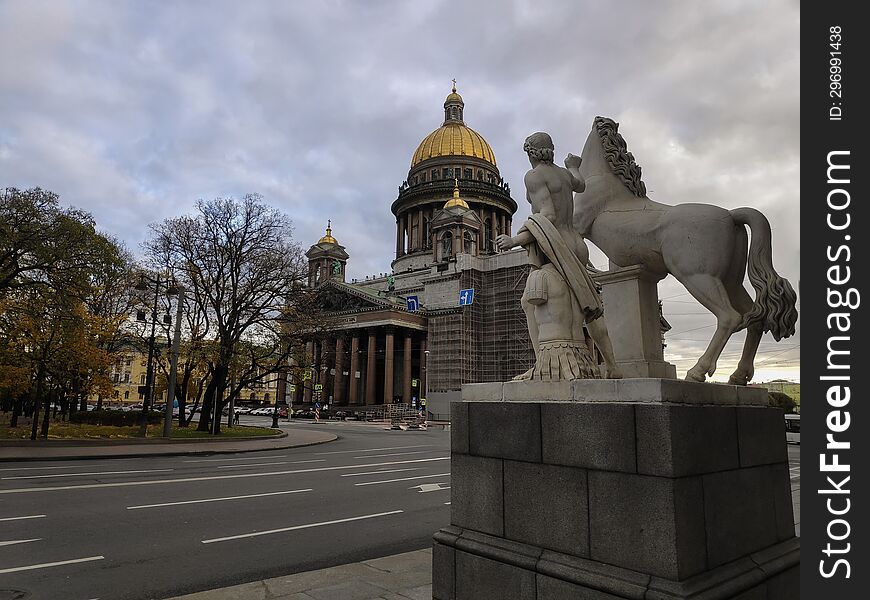 Statue of a man with a horse against the backdrop of the cathedral in St. Petersburg