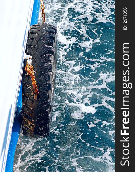 Tire tied to the side of a ship against foaming sea. Tire tied to the side of a ship against foaming sea.