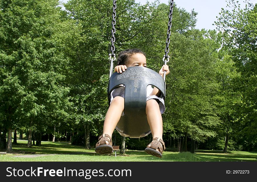 Toddler in baby swing at the park. Toddler in baby swing at the park