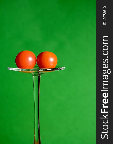 Two small tomatoes on a green background