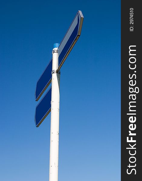 Empty road sign, two directions, isolated against a clear blue sky. Empty road sign, two directions, isolated against a clear blue sky