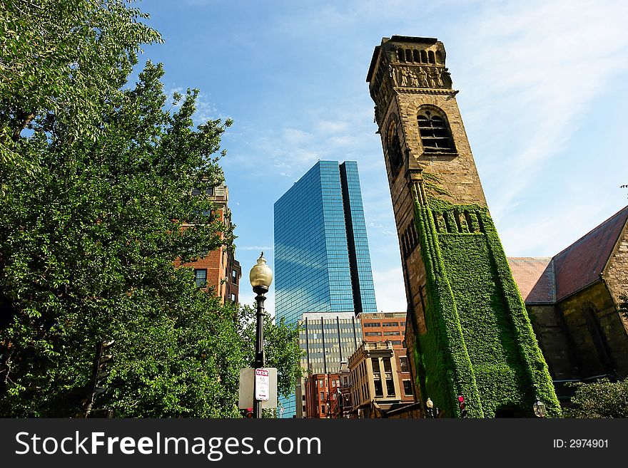 Wide angle view of one of the oldest church towers in boston with carvings of the apostles and angels, behind it is a modern glass skyscraper. Wide angle view of one of the oldest church towers in boston with carvings of the apostles and angels, behind it is a modern glass skyscraper