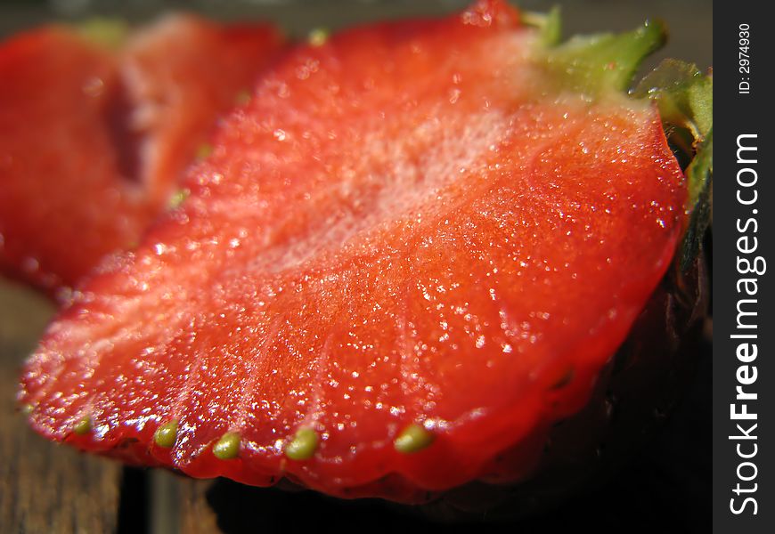 A macro shot showing a fresh strawberry fruit cut in two.