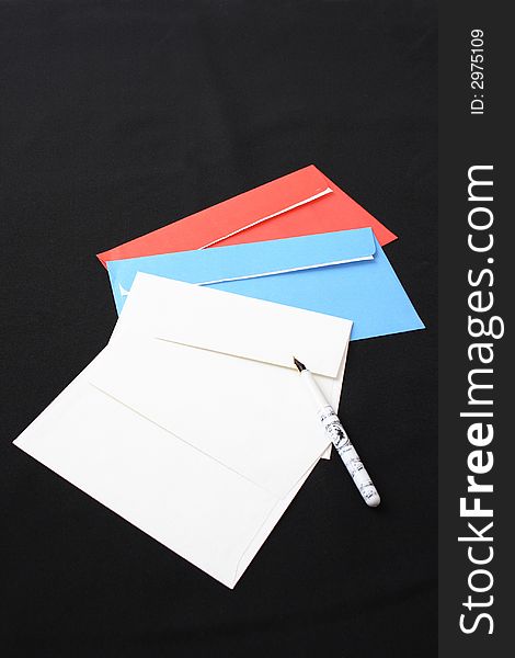 Multi-coloured envelopes and the pen on a black background