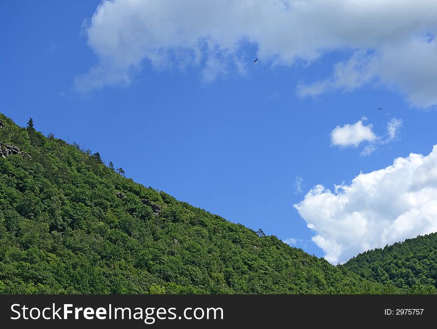 Green mountain slope and the blue sky with clouds.